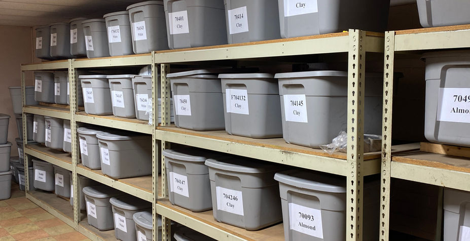 Dry storage are with shelving units of products in plastic bins.