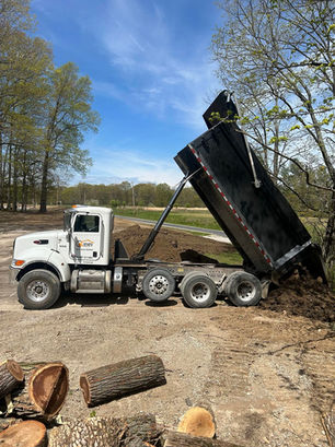 Dump truck unloading topsoil for grading and site work