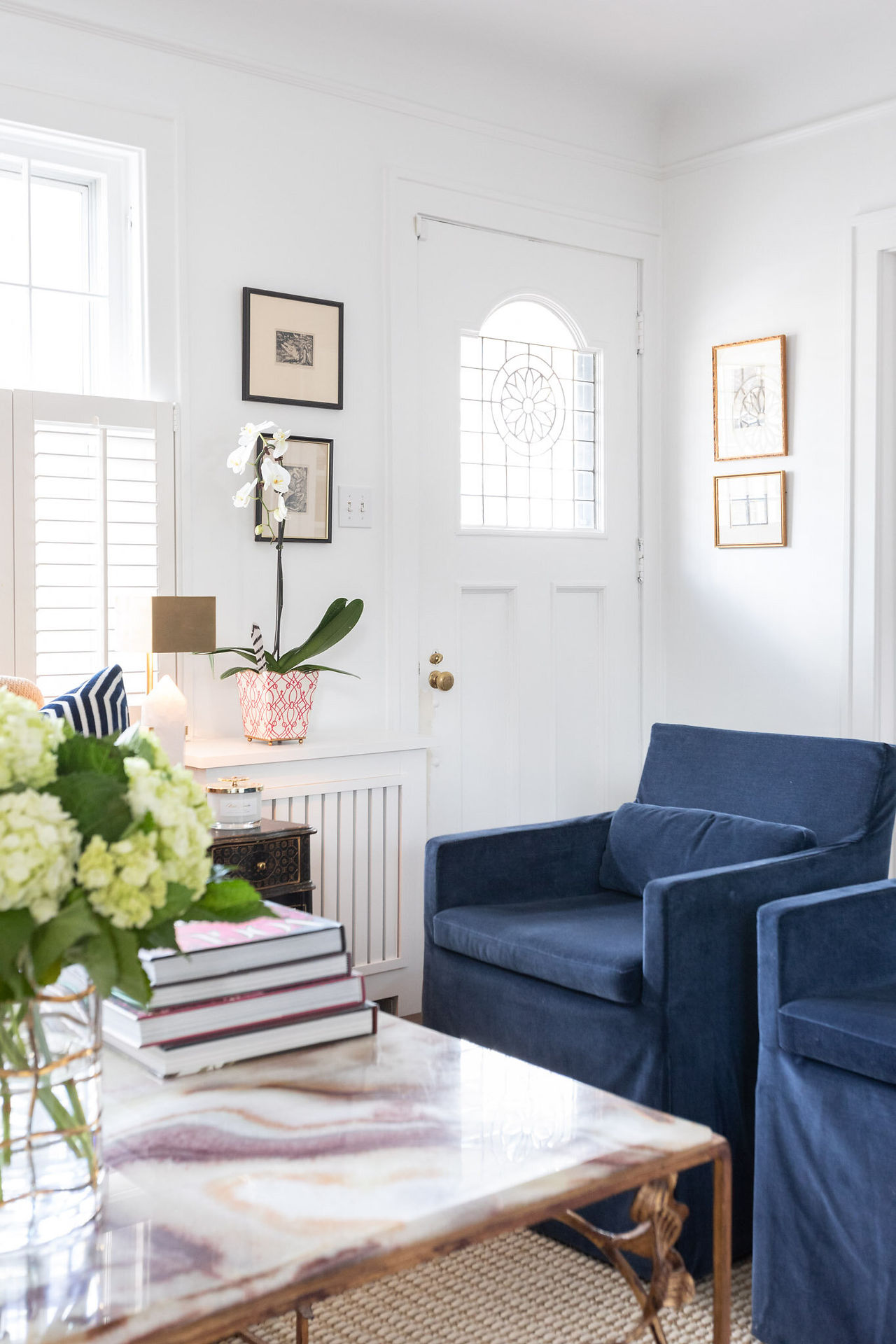 Front entryway with navy velvet chairs, white orchid, and stained glass door