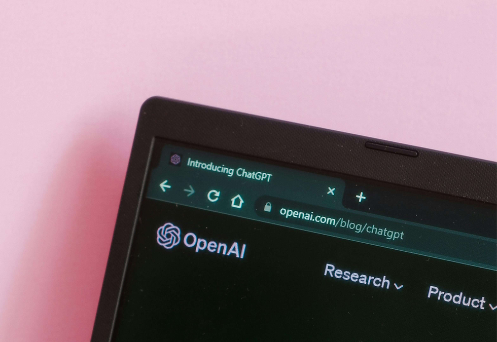 Close-up of a laptop with ChatGPT introduction on screen against a pink background.