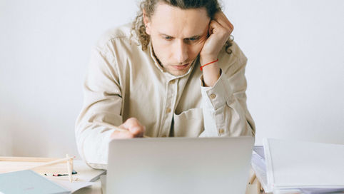 A marketer sitting at a desk looking at his laptop, frustrated with the SEO performance.