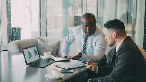 Two businessmen discussing data at a cafe while enjoying coffee and discussing their content repurposing strategy