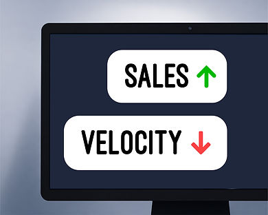 Monitor displaying "SALES" with a green up arrow and "VELOCITY" with a red down arrow on a dark background.