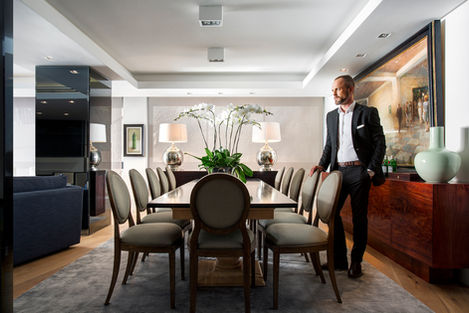 Chris Smit from Smit Collective stands in an elegant dining room he interior designed in Cape Town, wearing a modern suit.