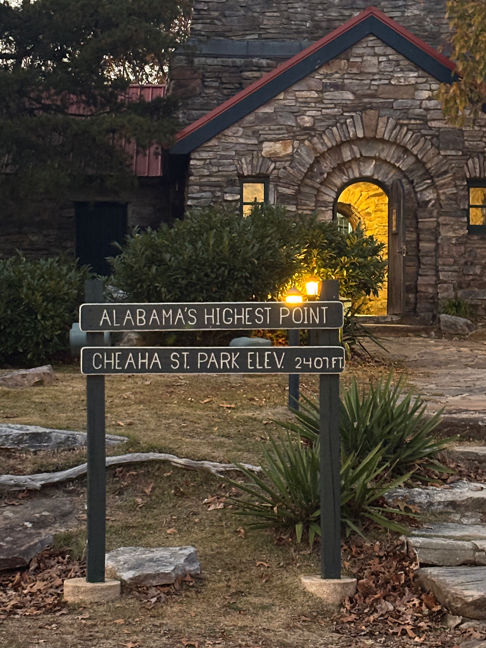 Rock building with a sign out front marking Alabama's highest point.