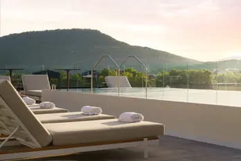 Rooftop infinity pool at Caption by Hyatt Chattanooga with lounge chairs and rolled towels, surrounded by painted pool deck surfaces finished by Dream Team Finishes, with Lookout Mountain in the background.