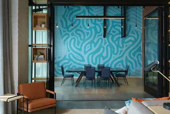 Bold teal custom mural wallcovering installed by Dream Team Finishes in a meeting room at Caption by Hyatt Chattanooga, visible through glass partition walls in the hotel lobby alongside painted brick walls.