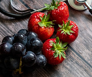 red-scottish-strawberries-and-black-grapes-with-stethoscope-on-top-of-wooden-table.jpg