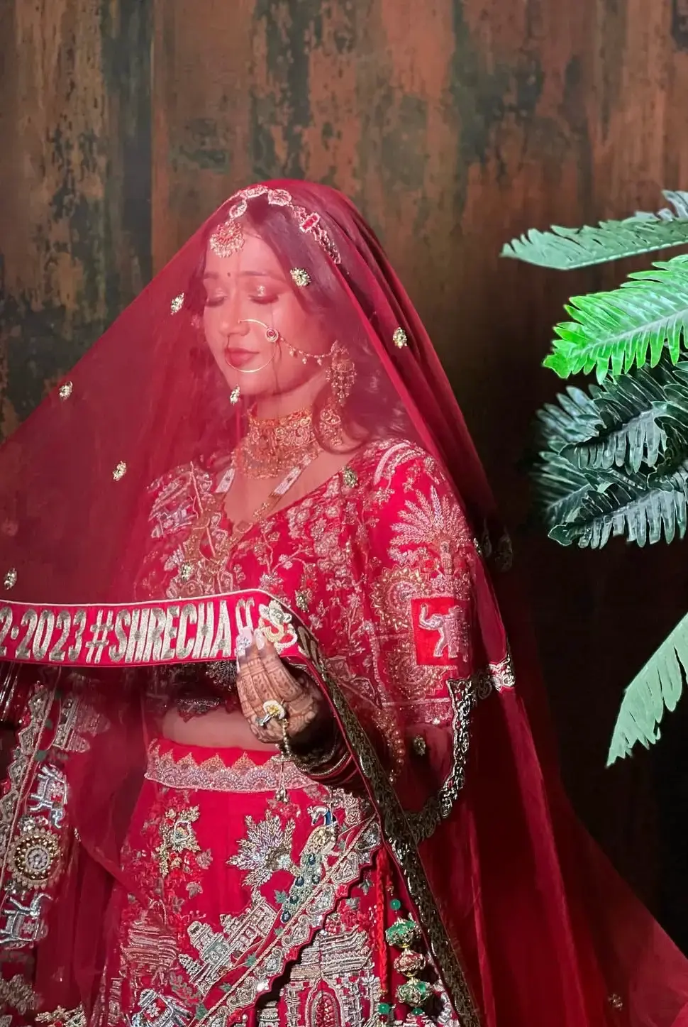 Bride in a designer red lahenga paired with a customised veil