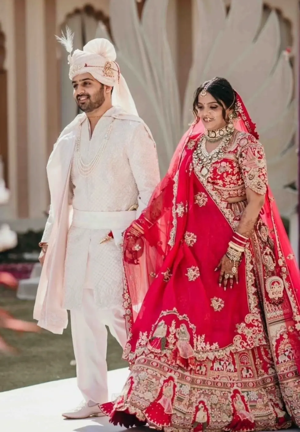 A couple doing their aisle walk by wearing traditional sherwani and lehenga