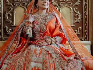 bride sitting by wearing a orange embroidered lehenga with matching jewellery