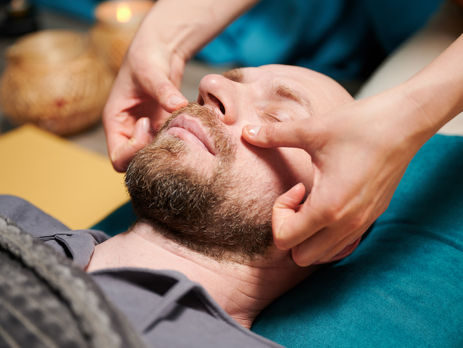 Man receiving craniosacral therapy from female massage therapist.
