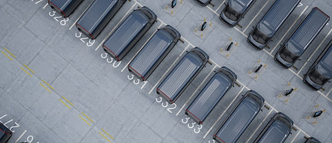 Overhead high angle drone shot of fleet modern electric EV delivery vans standing in compa