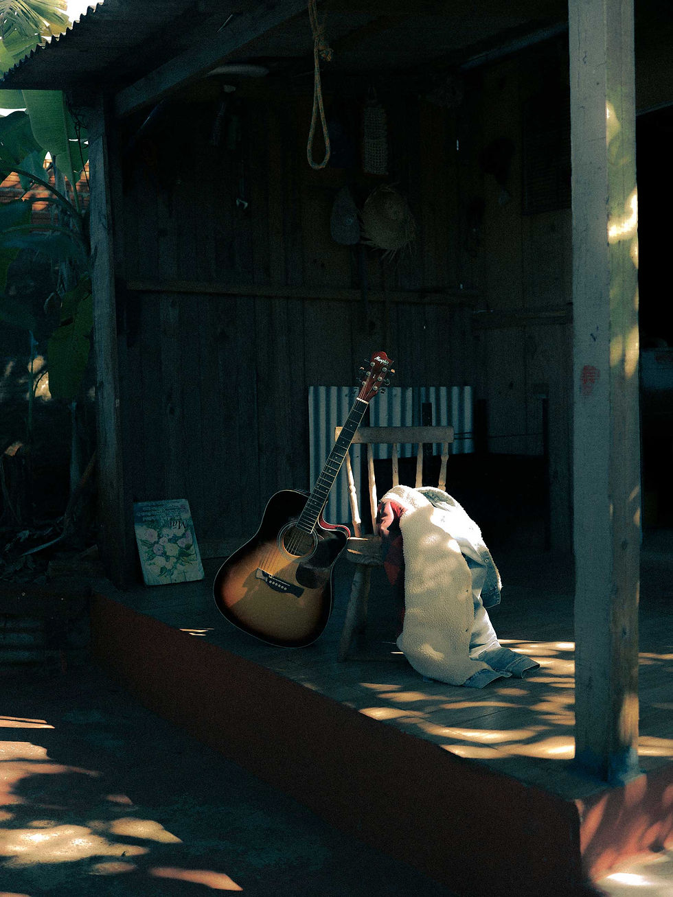 Acoustic guitar resting on the porch of a rustic countryside cabin