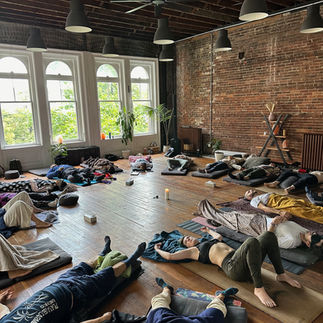 Group Somagetic Breathwork session with participants lying down in rows, focusing on energetic release and healing.