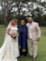 Newlyweds with officiant near outdoor wedding decorations