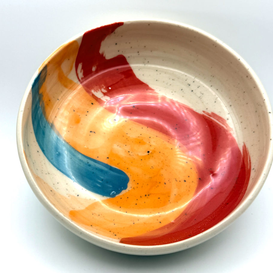Handcrafted speckled ceramic bowl with abstract red, orange, and blue brushstrokes.
