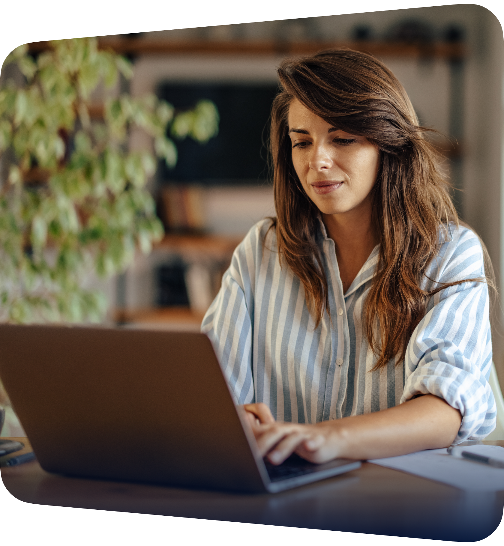 A smiling woman working on a laptop in a green office