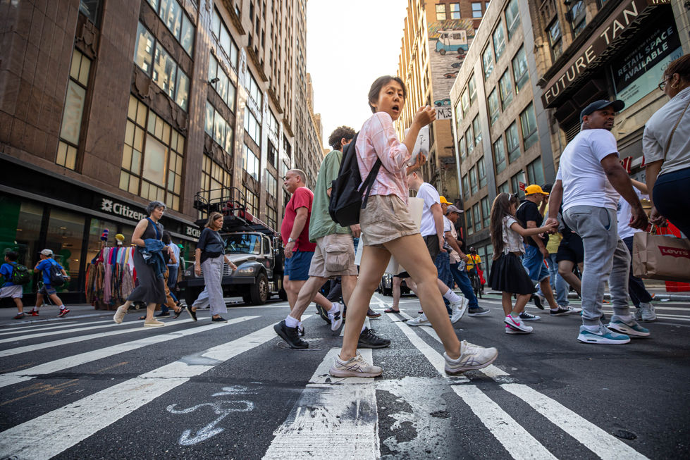 anhattan street photography showing a low-angle view of people crossing a busy crosswalk among tall buildings.