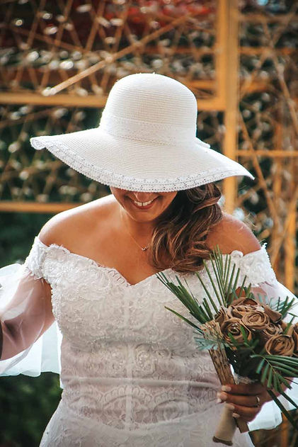 Mariée souriante en robe de dentelle avec chapeau blanc.