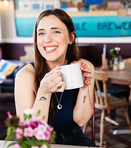 Claire Hill holding a coffee cup and smiling at the camera