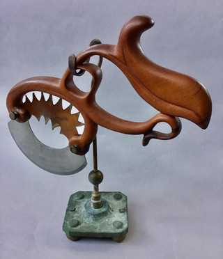 Pizza cutter handmade carved Sapele wood frame with decorative copper insert above crescent cutting blade; Brass & copper stand. 1910