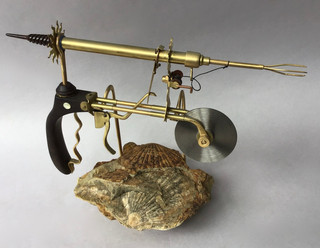 Handmade pizza cutter from submarine Nautilus, dark wood handle, brass cutter frame and harpoon launcher; stand of fossil clams. 1870
