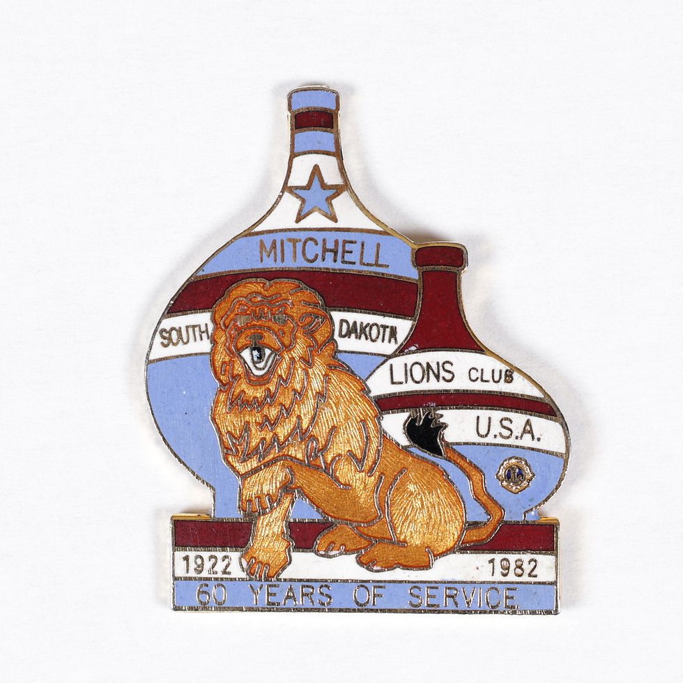 Pin's Lions Club Mitchell South Dakota USA en métal émaillé représentant un lion doré devant deux bouteilles décoratives,