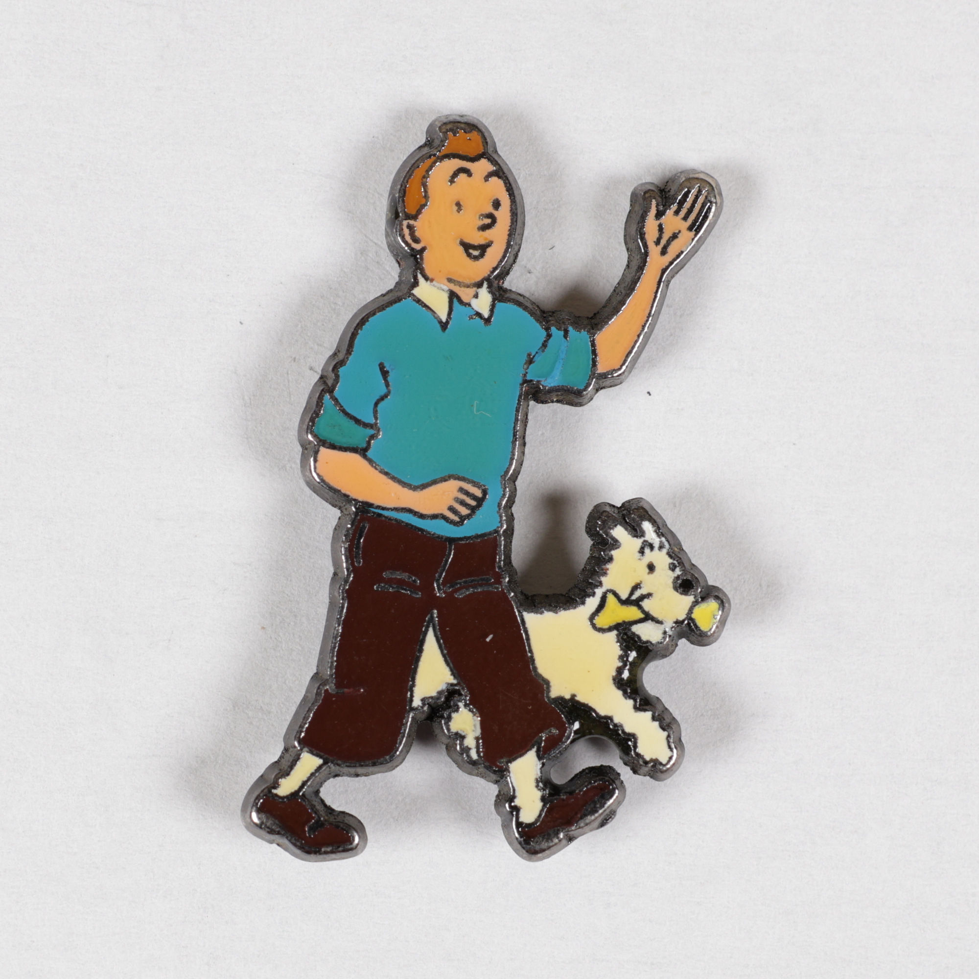 Pin's Tintin représentant le jeune reporter en pull bleu et pantalon marron, marchant avec son chien Milou à ses côtés