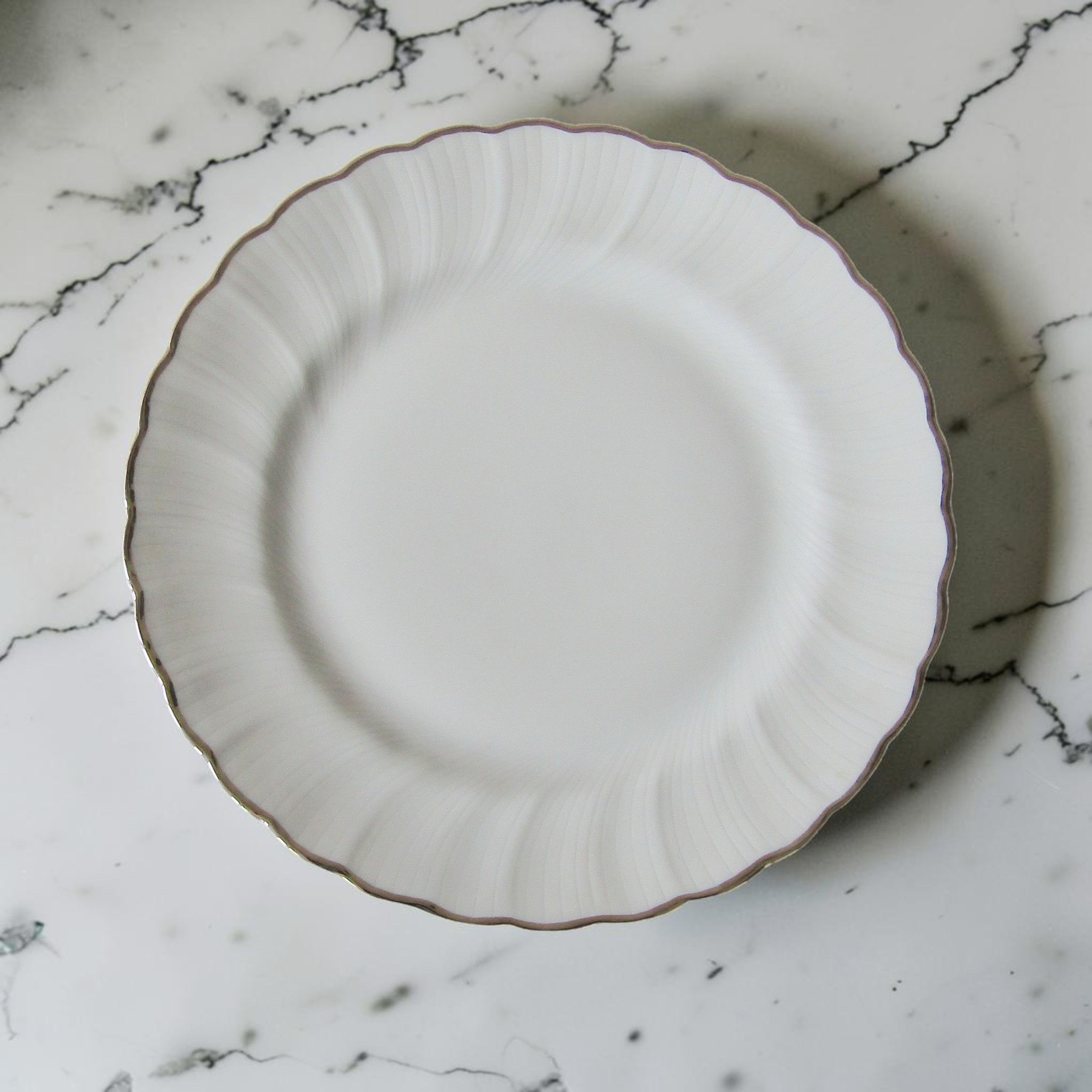 Assiette plate en porcelaine de Limoges Bernardaud modèle Verdi avec relief strié rayonnant et bord ondulé souligné