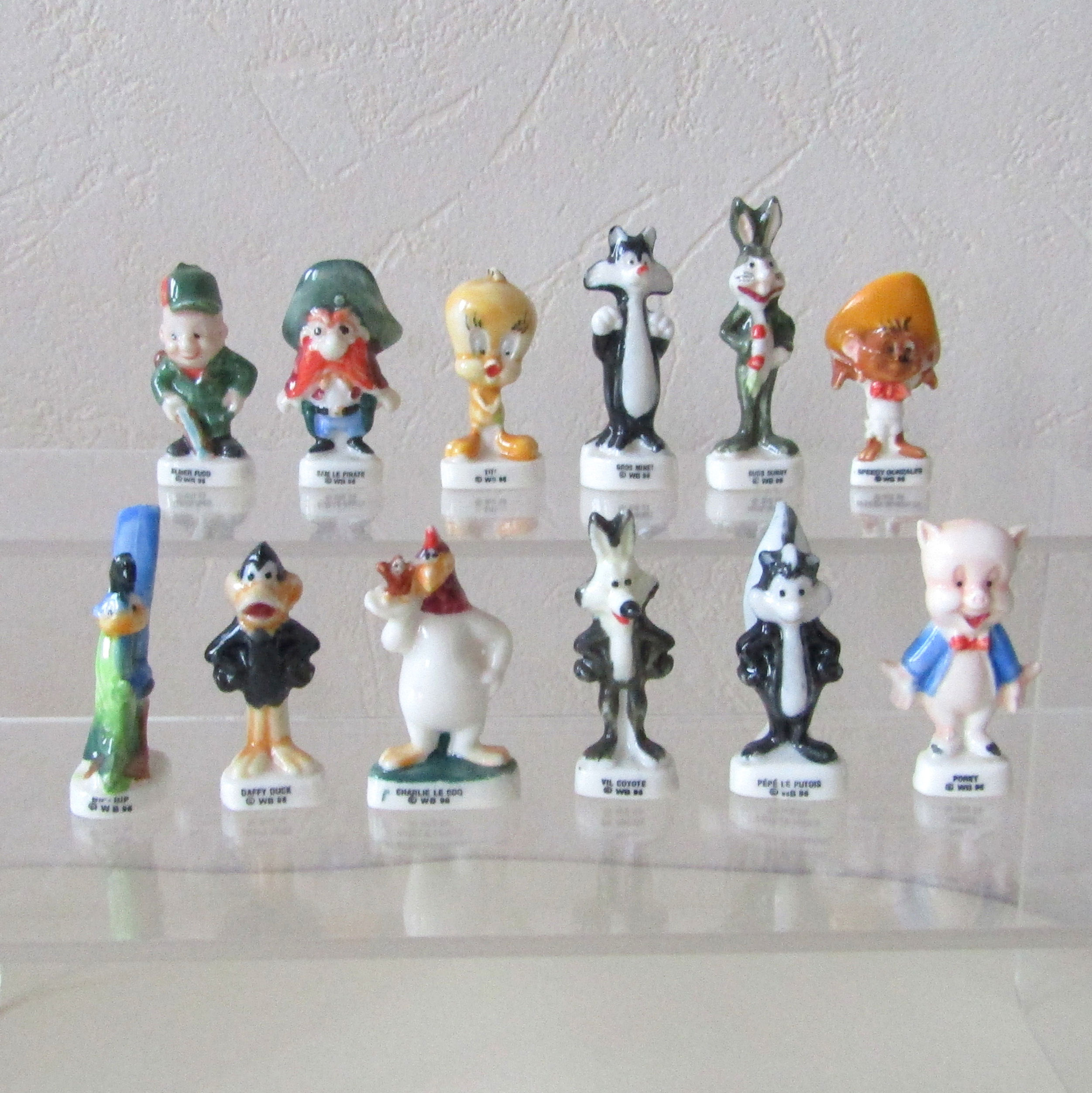 Série de 12 fèves brillantes en porcelaine Bugs Bunny et ses Amis (Éditions Alcara) représentant les personnages emblématique