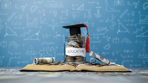 Jar of coins topped with graduation cap and tassels, surrounded by paper money rolls on an open book