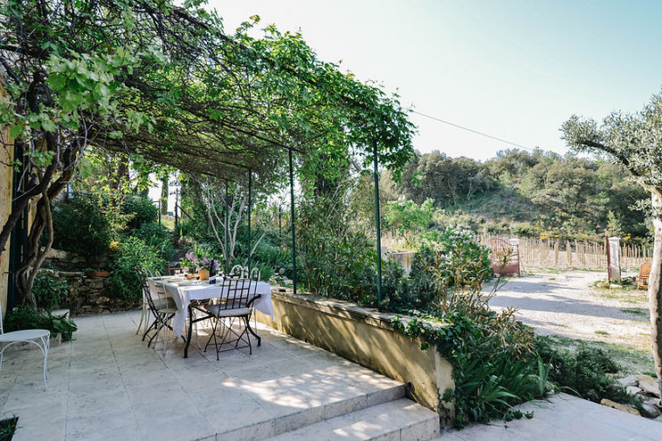 Terrasse extérieure et table au Mas préparé pour un dîner avec une bouteille de vin du Clos de Caveau, idéaux pour se détendre et profiter de la vue.