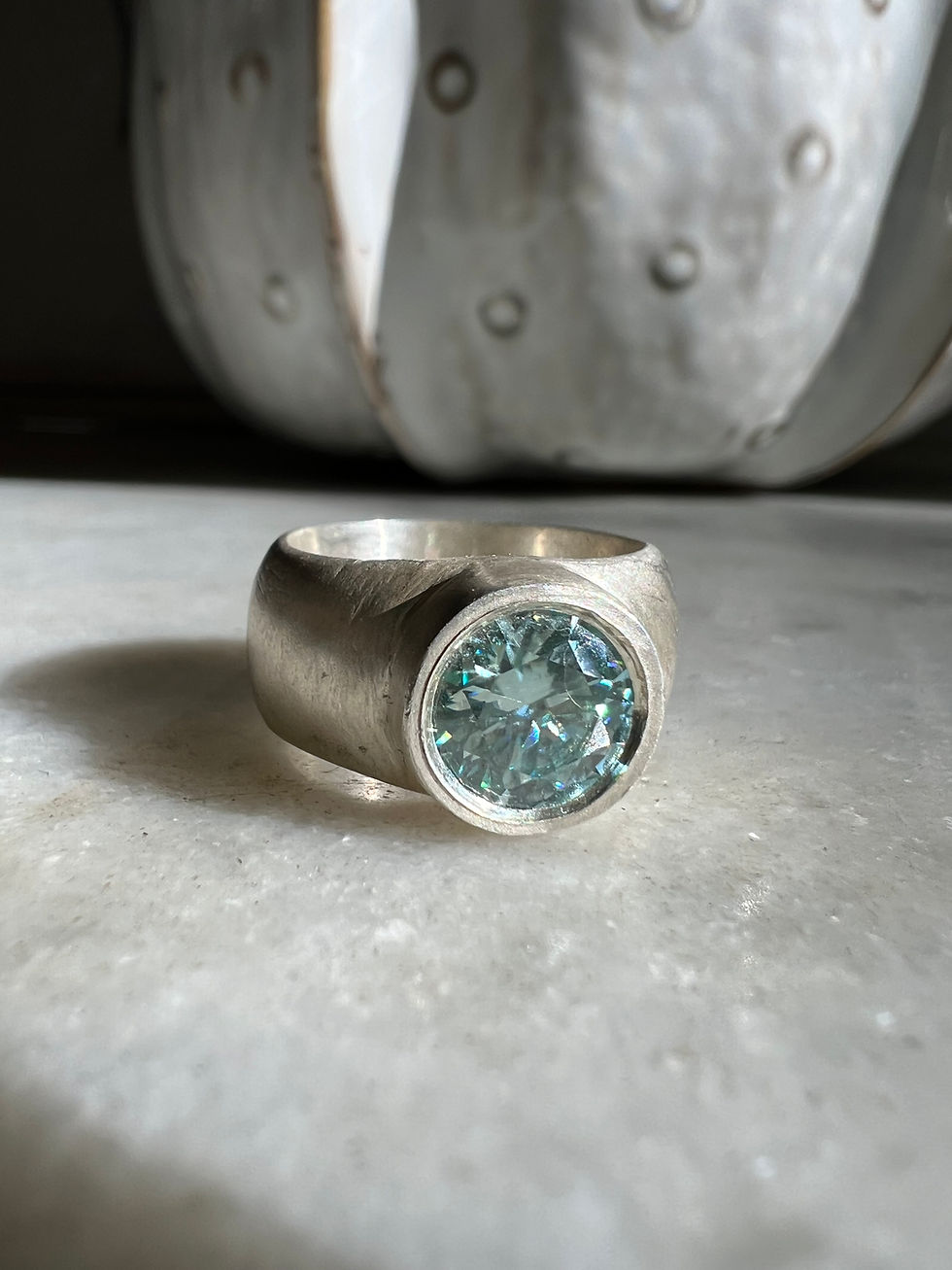 Thumbnail: Handmade teal moissanite silver ring with thick band and brushed texture.