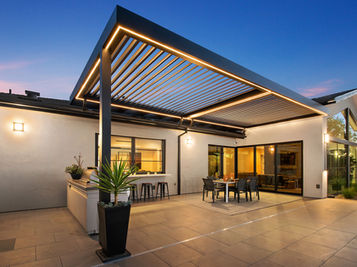 Louvered pergola featuring warm orange lighting, highlighting the architectural design under the sky.