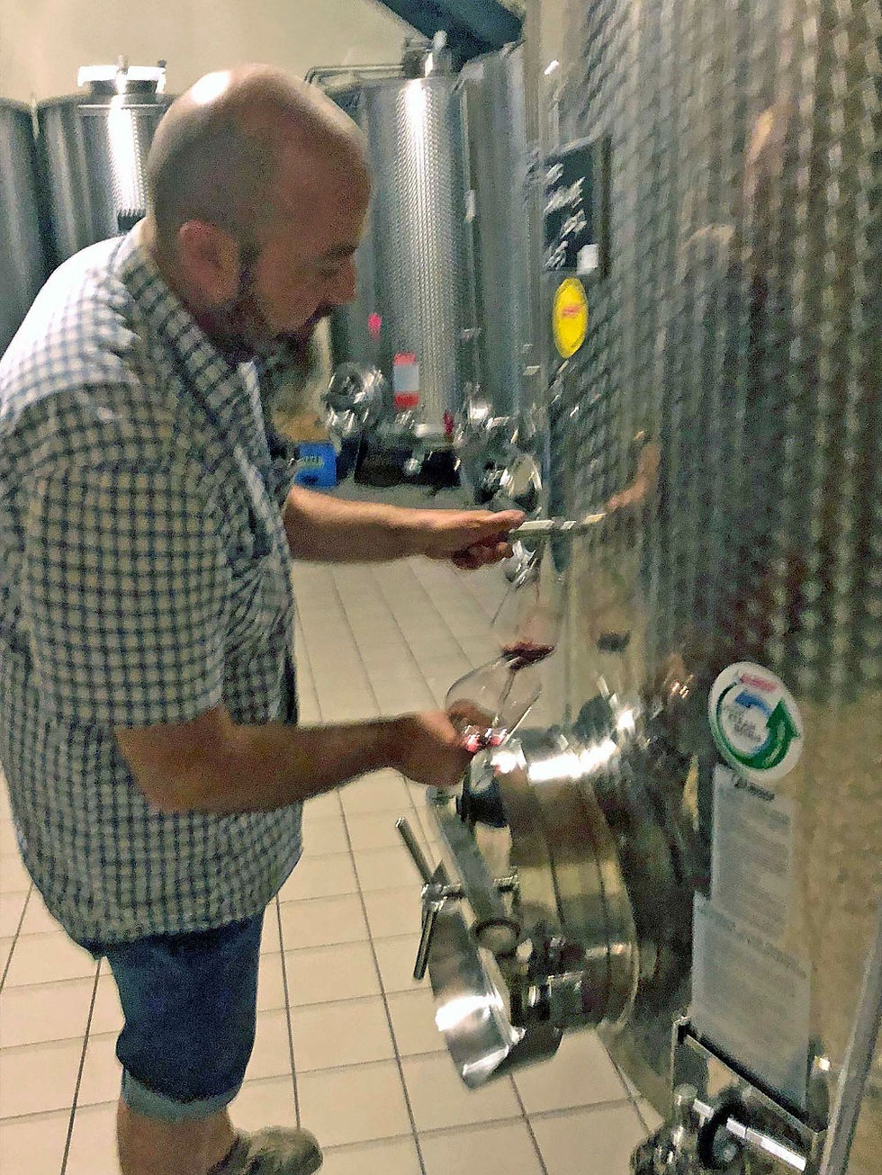 Winemaker pouring wine from a wine tank at Fratelli Vogadori Winery