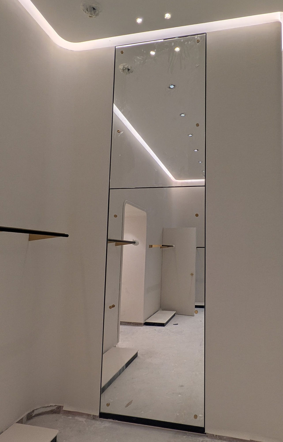 Full-height mirror panel set into a curved wall, with bronze-finish wall rails