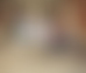 A group of people, including a man in a tie, walk down stone steps in front of a brick building with columns. Casual attire, daytime.