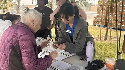 An older woman interacting with a young staff member at an outdoor tabling activity.