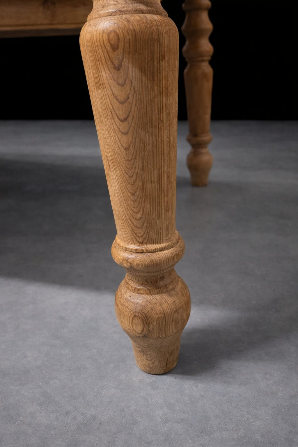 Detail of antique English farmhouse pine dining table turned leg showing traditional craftsmanship