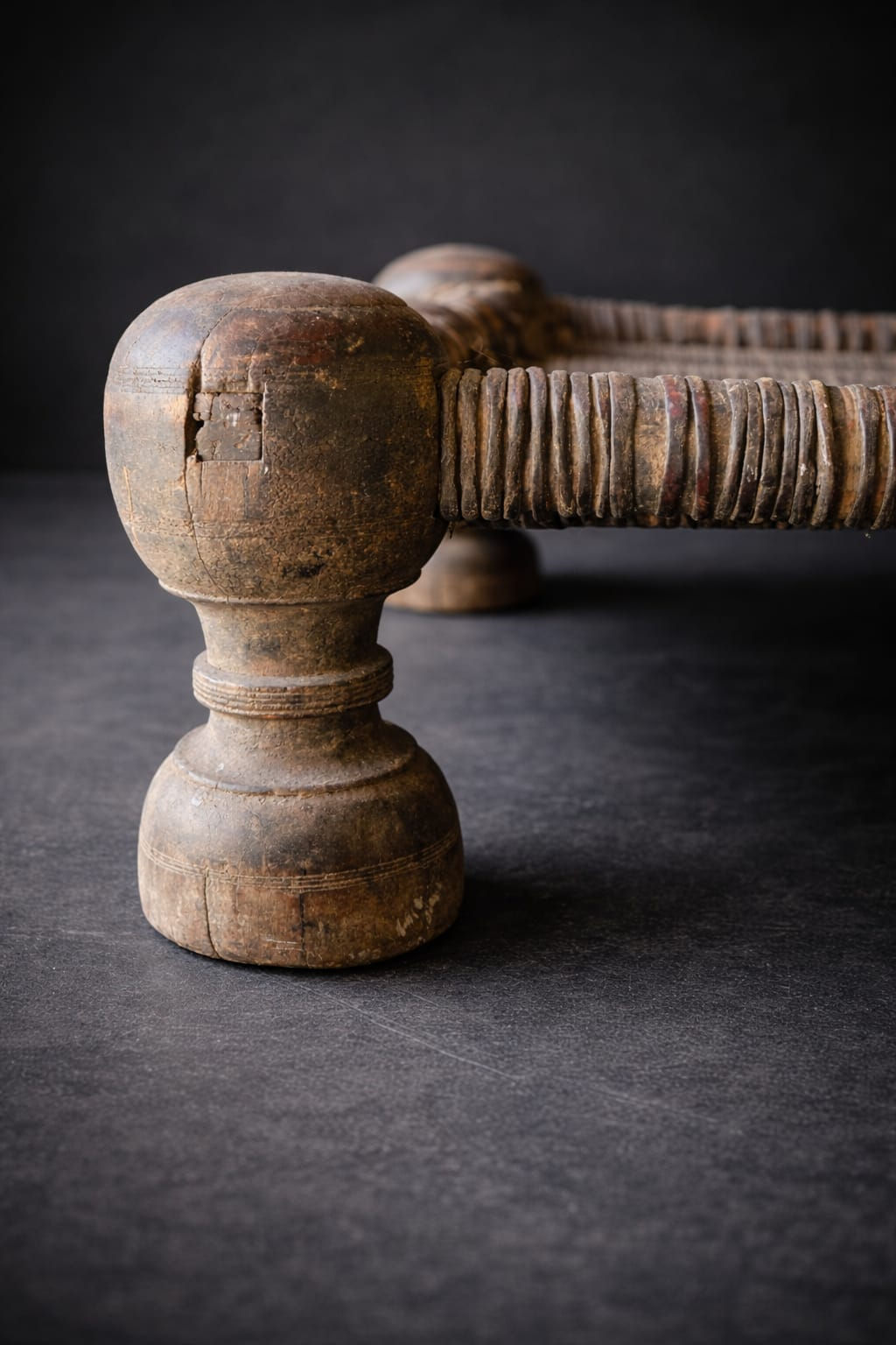 Detail of hand-carved wooden leg and rope weaving on antique Indian charpoy stool