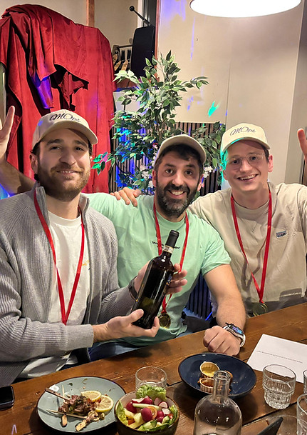 Three quiz winners wearing medals. One person holds a bottle of wine.