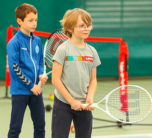 Enfant qui tient une raquette de tennis heureux