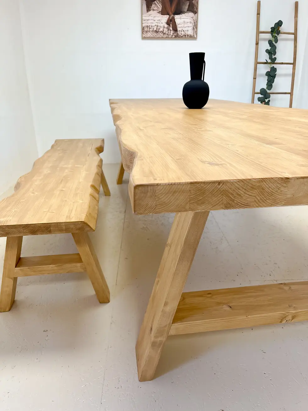 GRANDE TABLE À MANGER EN ÉPICÉA MASSIF AVEC BORDS NATURELS ET PIÈTEMENT TRÉTEAU DANS UN INTÉRIEUR LUMINEUX