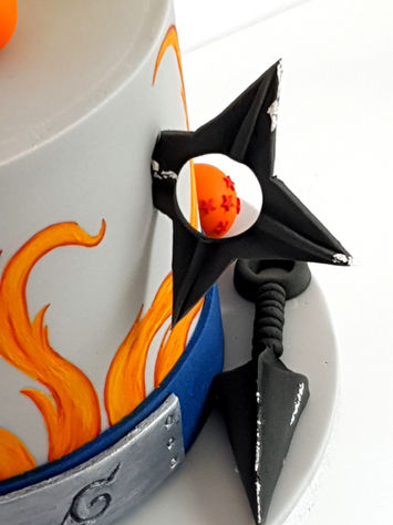 Sugar models on a cake: a Dragon Ball through a shuriken, with a kunai on the side below.