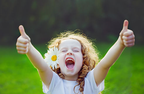 Laughing girl with daisy in her hairs, showing thumbs up..jpg