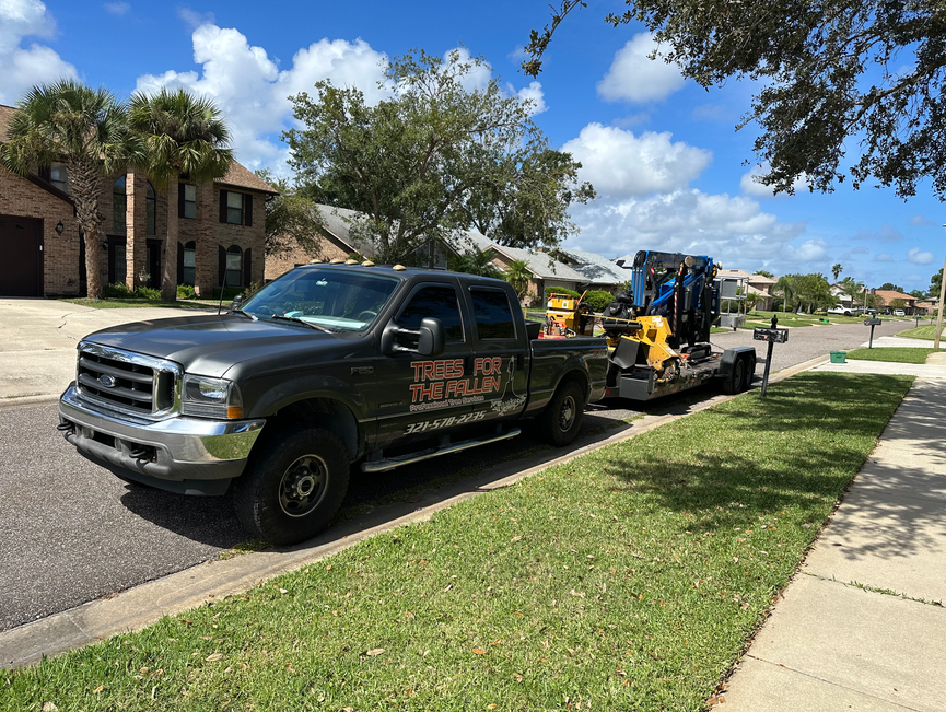 A dark work truck and equipment trailers staged along a residential street.