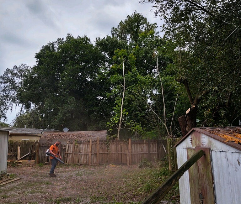 A crew member walking across a dusty cleared lot between small sheds in Edgewater, Florida.