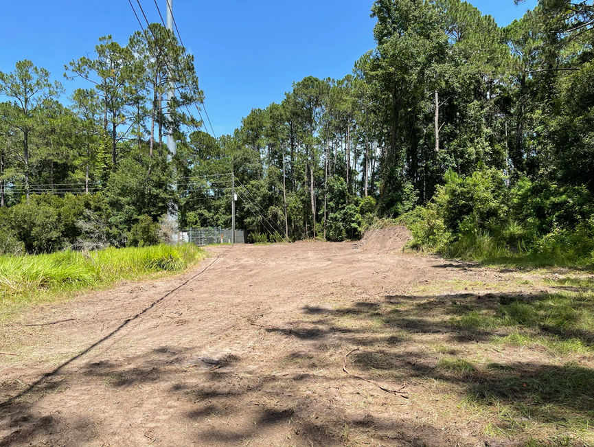 A flat dirt pad cleared out of the woods, with trees still standing around the edge in Edgewater, Florida.