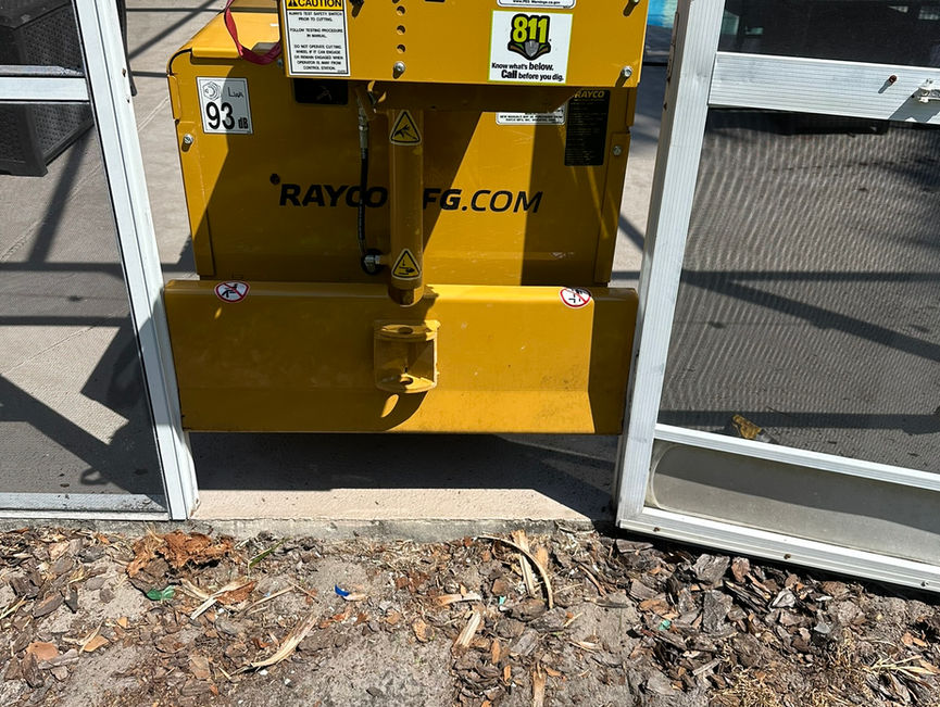 A yellow Rayco stump grinder sitting at an open screen door in Port Orange, Florida.